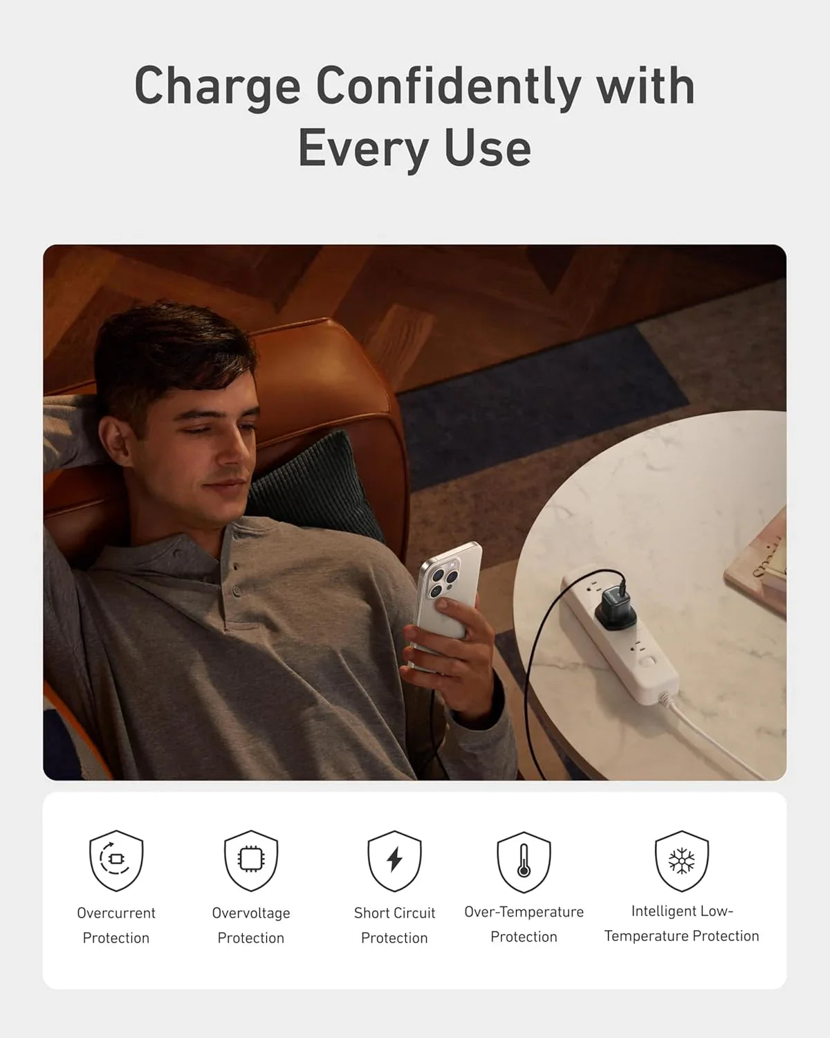 Man charging phone with Anker power strip featuring safety protections, Anker Kuwait