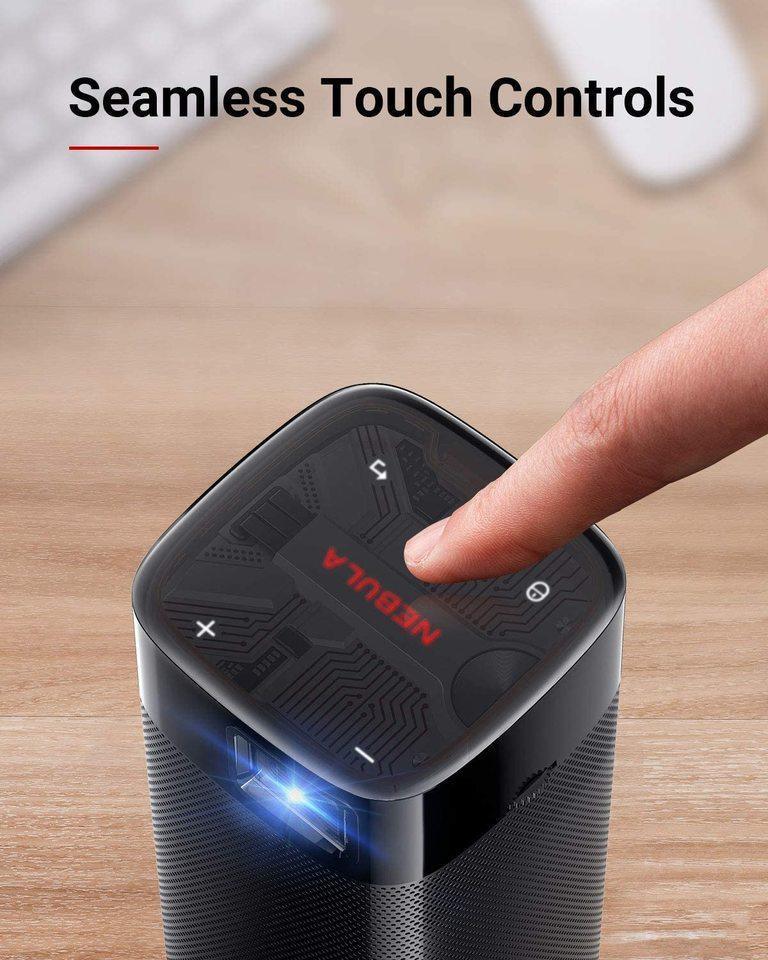 Anker Nebula projector with seamless touch controls, finger tapping top panel on wooden desk